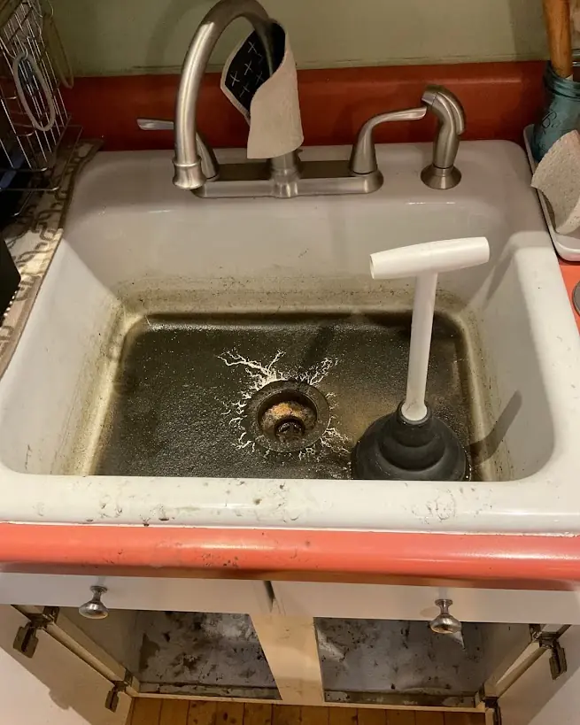 Kitchen sink fully backed up with standing dark water before Drain Master NJ clog removal at a New Jersey home