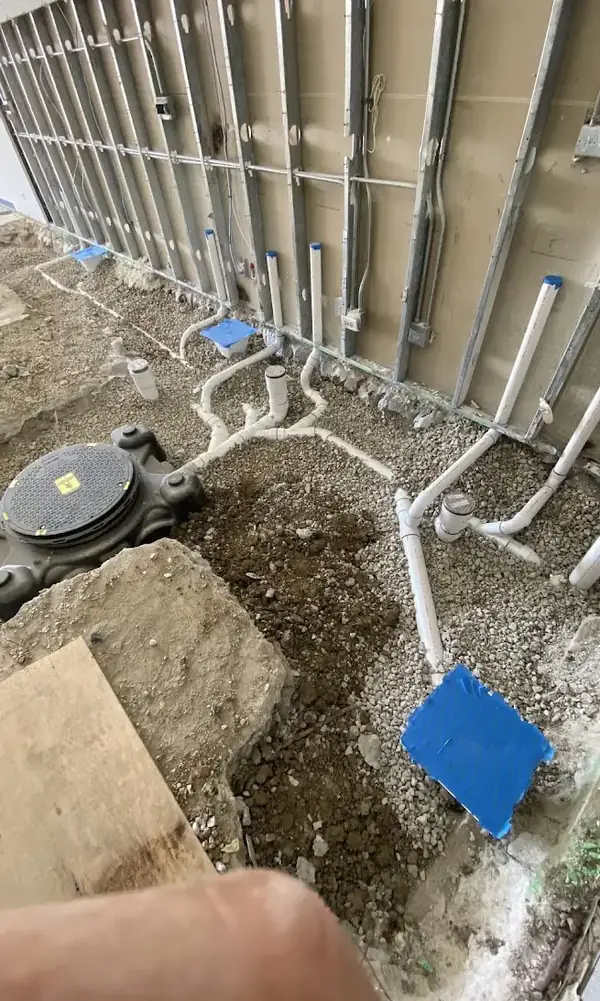 New commercial drainage rough-in with branch piping and ejector basin on gravel at a New Jersey business