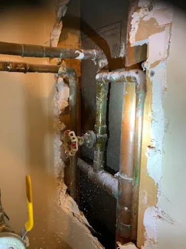 In-Wall Pipe Repair Access — Drain Master NJ Aging pipes exposed behind a wall opening for a targeted repair at a New Jersey home