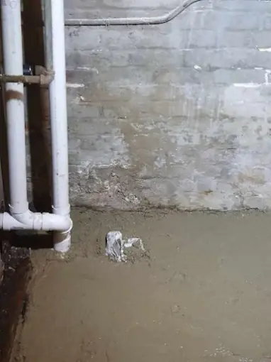 Basement floor patched and restored after an under-floor drain line repair at a New Jersey home